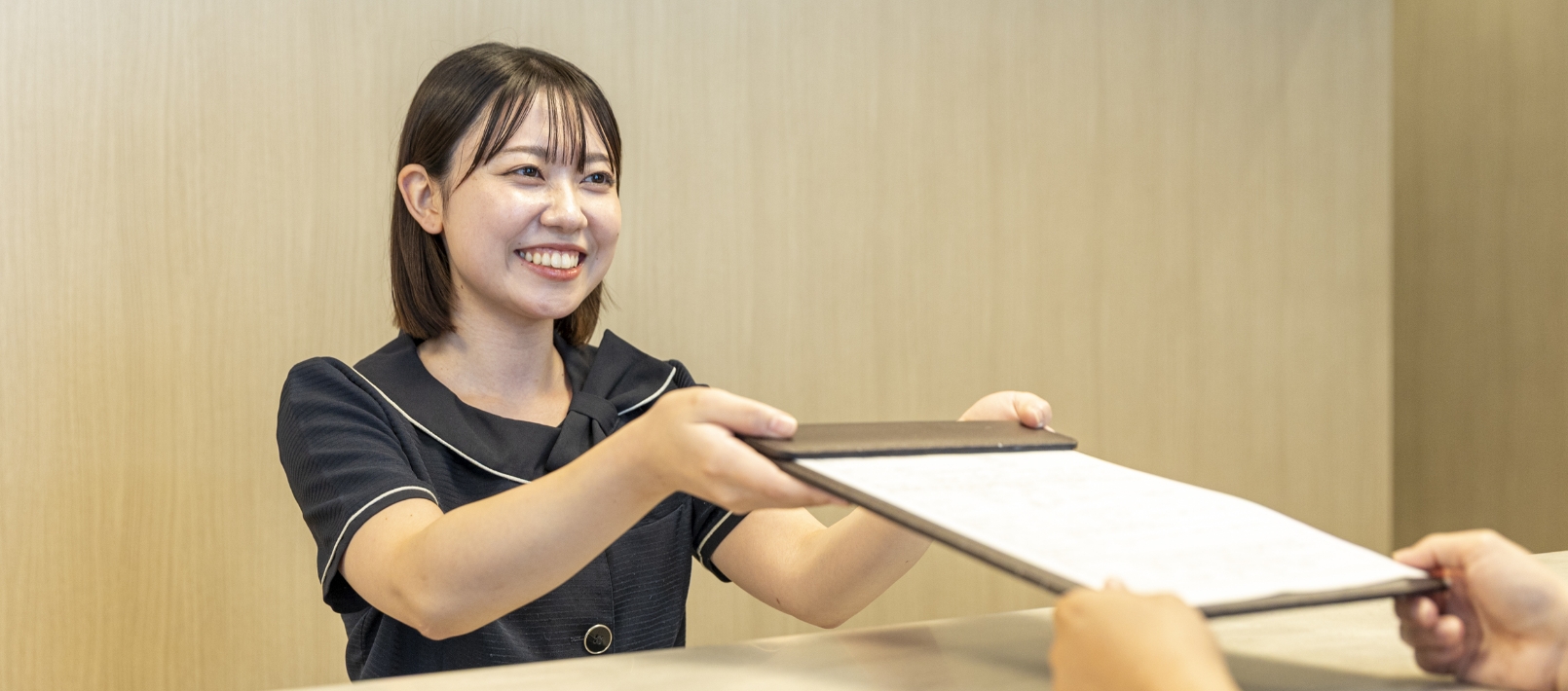 来院した患者を笑顔で案内する受付スタッフ